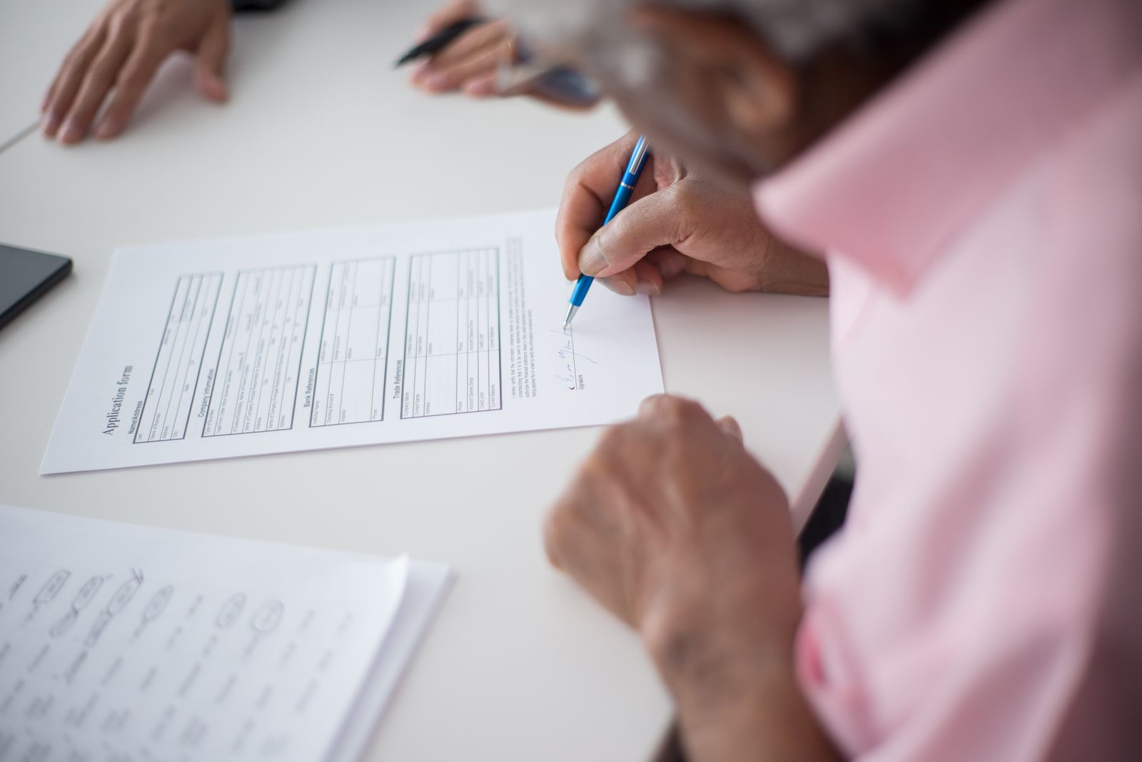 Hands signing a document at a desk